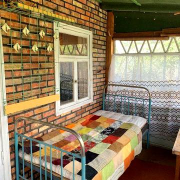 Невеличкий будинок з червоної цегли з пічкою та лежанкою біля лісу
